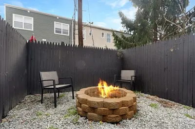 a fire pit in a backyard with two chairs and a fence at Luxury Duplex in Hoboken 15Min to NYC, Fire Pit in Jersey City