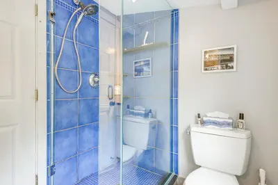 a blue tiled bathroom with a toilet and a shower at 2 Mi to Mt Snow Cozy Family Alpine Retreat! in Wardsboro