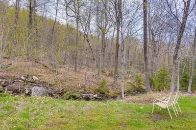 a chair sitting in the grass in the woods at 2 Mi to Mt Snow Cozy Family Alpine Retreat! in Wardsboro