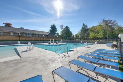 a group of blue chairs sitting around a swimming pool at Poconos Family Home with Lake Access and Game Room in Tobyhanna