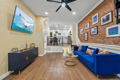 a living room with a blue couch and a brick wall at Free Parking -NEW 3BR-2Bath, 5 Beds, 10 Min to NYC, Sleeps 7 in Hoboken