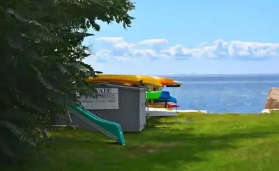 a playground with a slide and a boat on the water at Enchanted Cottage 1 block to beach in Madison