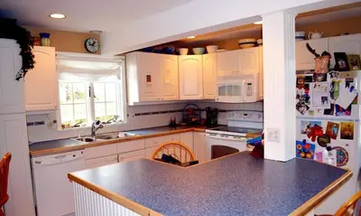 a kitchen with white cabinets and a black counter top at Enchanted Cottage 1 block to beach in Madison
