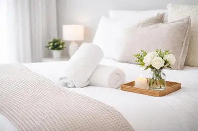 a white bed with a candle and flowers on it at New Haven Staycation Near Yale Washer and Dryer Groups in New Haven