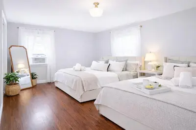 a white bedroom with two beds and a mirror at New Haven Staycation Near Yale Washer and Dryer Groups in New Haven
