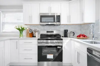 a white kitchen with a stove and a microwave at New Haven Staycation Near Yale Washer and Dryer Groups in New Haven