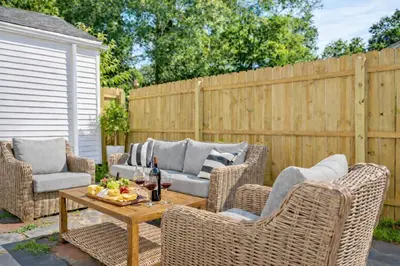 a patio with wicker chairs and a table with a bottle of wine at New Haven Staycation Near Yale Washer and Dryer Groups in New Haven