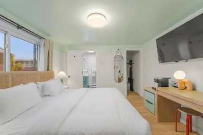 a bedroom with a large white bed and a kitchen at Ambler Hotel in Saratoga Springs
