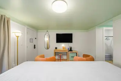 a bedroom with a bed and a desk and a television at Ambler Hotel in Saratoga Springs