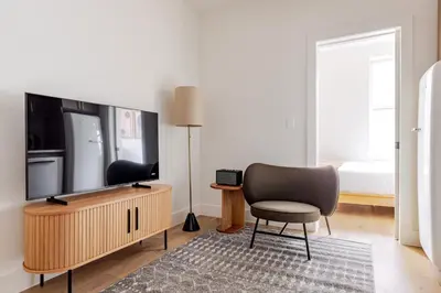 a living room with a chair and a flat screen tv at Blueground Manhattan wd AC nr park NYC-1829 in New York