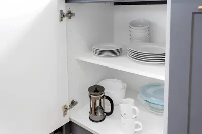 a cupboard filled with white plates and dishes at Chic Studio Close to Harbor Point in Stamford