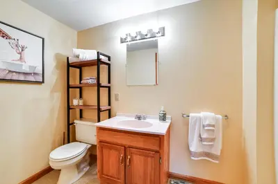 a bathroom with a toilet and a sink and a mirror at Hike and Baseball Near Cooperstown Home on 30 Acres in Westford