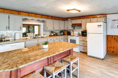 a kitchen with white appliances and a counter with stools at Hike and Baseball Near Cooperstown Home on 30 Acres in Westford