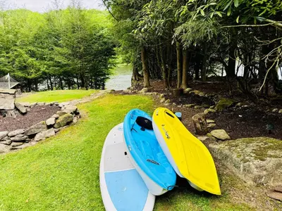 two boats sitting on the grass next to a river at Lazy River Cabin: Lakefront Stay in Greentown