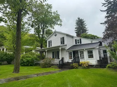 a white house with a yard at Book Village Inn - Dickinson Room Queen Bed in Hobart