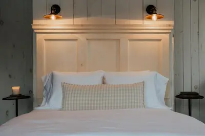 a bed with white pillows and a headboard with lights at Book Village Inn - Dickinson Room Queen Bed in Hobart