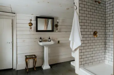 a white bathroom with a sink and a mirror at Book Village Inn - Dickinson Room Queen Bed in Hobart