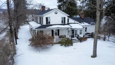 a white house with snow on the ground at Book Village Inn - Dickinson Room Queen Bed in Hobart