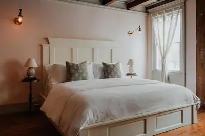 a bedroom with a large bed with white sheets and a window at Book Village Inn - Fitzgerald Room King Bed in Hobart
