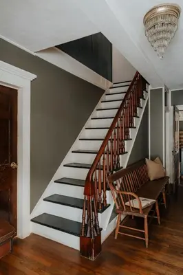 a staircase in a house with a chair and a chandelier at Book Village Inn - Fitzgerald Room King Bed in Hobart
