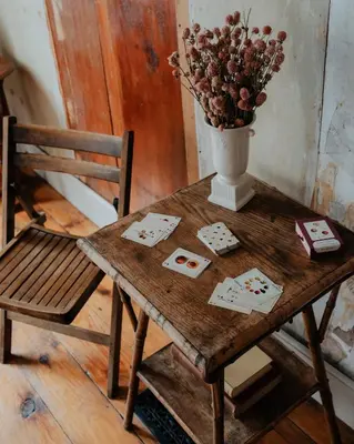 a wooden table with a vase of flowers and a chair at Book Village Inn - Fitzgerald Room King Bed in Hobart
