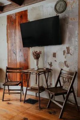 a table with two chairs and a television on a wall at Book Village Inn - Fitzgerald Room King Bed in Hobart