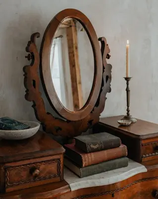 a mirror on top of a table with books and a candle at Book Village Inn - Hemingway Room King Bed in Hobart