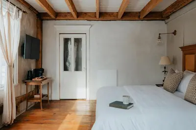 a bedroom with a white bed and a door at Book Village Inn - Hemingway Room King Bed in Hobart