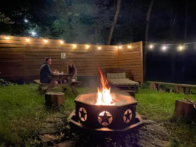 a man and woman sitting at a table around a campfire at Mountain Lodge Retreat, Near New Paltz & Hikes in New Paltz