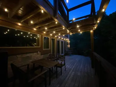 a deck with a wooden table and chairs and lights at Mountain Lodge Retreat, Near New Paltz & Hikes in New Paltz
