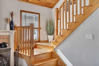 a wooden staircase in a home with white walls at Wooded lakefront chalet with hot tub and game room in South Kortright