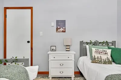 a bedroom with a white bed with a nightstand and a bed sidx sidx sidx at Wooded lakefront chalet with hot tub and game room in South Kortright