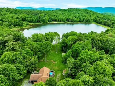 an aerial view of a lake in the woods at Wooded lakefront chalet with hot tub and game room in South Kortright