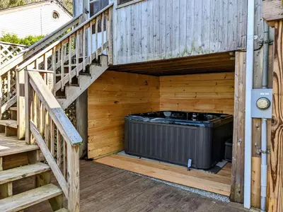 a hot tub under a wooden deck with stairs at Catskills Lakefront with Kayaks, HotTub & Firepit in Swan Lake