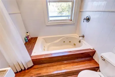a bathroom with a tub and a toilet and a window at Catskills Lakefront with Kayaks, HotTub & Firepit in Swan Lake