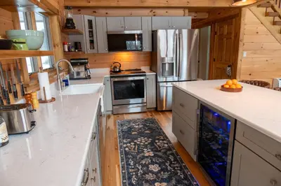 a kitchen with white counter tops and wooden floors at Fully Loaded Riverfront West Branch Fishing Cabin in Deposit
