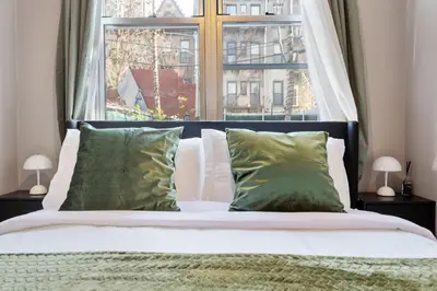 a bed with green pillows in front of a window at 5BD Duplex w Private Patio BBQ and Arcade Games in Brooklyn