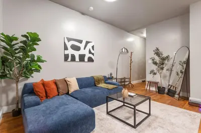 a living room with a blue couch and a table at 5BD Duplex w Private Patio BBQ and Arcade Games in Brooklyn