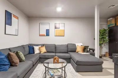a living room with a gray couch and a table at 5BD Duplex w Private Patio BBQ and Arcade Games in Brooklyn
