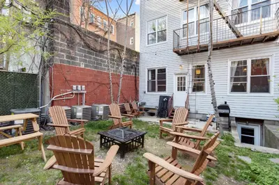 a group of wooden chairs and tables in a yard at 5BD Duplex w Private Patio BBQ and Arcade Games in Brooklyn