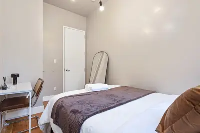 a bedroom with a bed and a desk and a mirror at 5BD Duplex w Private Patio BBQ and Arcade Games in Brooklyn