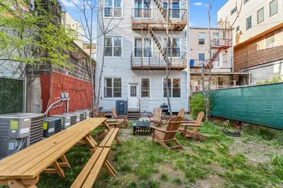 a backyard with picnic tables and a building at 5BD Duplex w Private Patio BBQ and Arcade Games in Brooklyn