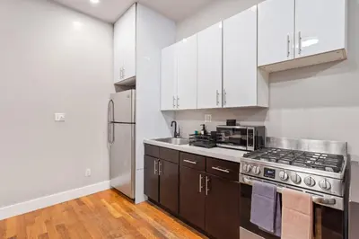 a kitchen with white cabinets and a stove top oven at 5BD Duplex w Private Patio BBQ and Arcade Games in Brooklyn