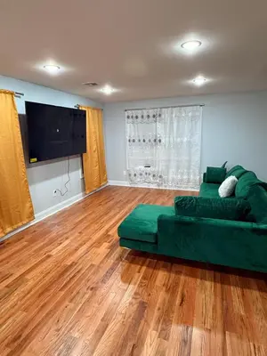 a living room with a green couch and a flat screen tv at E&G homes in East Orange