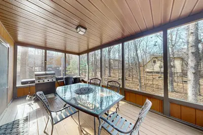 a screened in porch with a glass table and chairs at Burntwood Retreat in East Stroudsburg