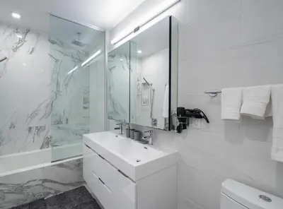 a white bathroom with a sink and a shower at Stunning Apartment in Manhattan with Patio in New York