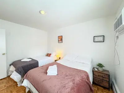 two beds in a room with white walls at Spacious and Convinient near NYC Parking Available in Guttenberg