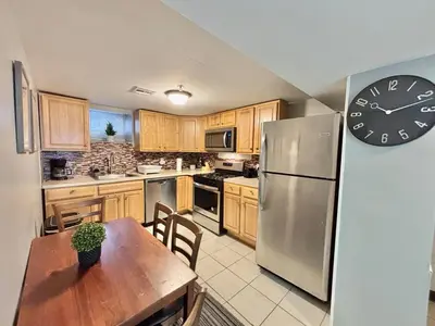 a kitchen with a refrigerator and a table with a clock at FREE Parking Cozy 2 Bedroom unit near NYC in North Bergen