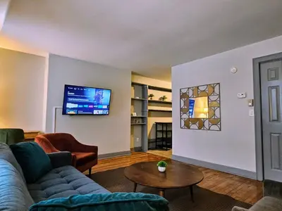 a living room with a couch and a tv on a wall at Massive 5BD/4BA 3-Story Duplex @ Downtown Albany in Albany