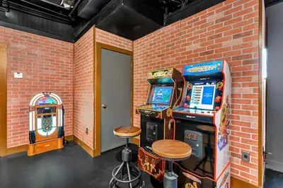 a room with two arcade machines next to a brick wall at 5BR Lux Cabin w HotTub Sauna Pool FirePit GameRoom in East Stroudsburg